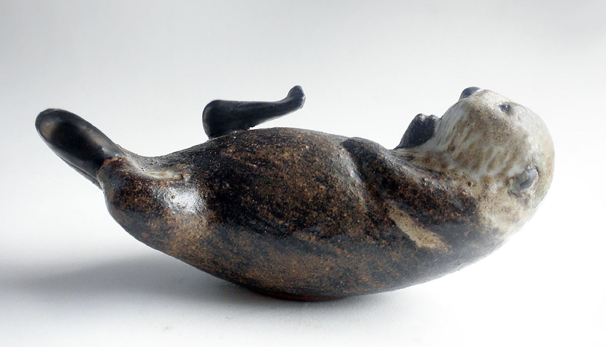 Sea Otter by Christine Andersen in brown slip and white glaze with bronze accents